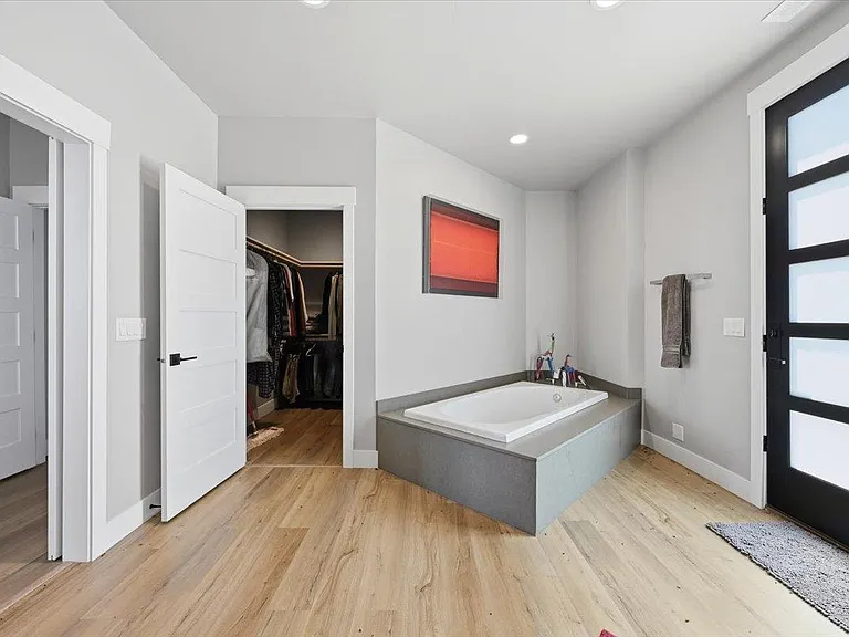 A stone-clad soaking tub sits near a red abstract artwork