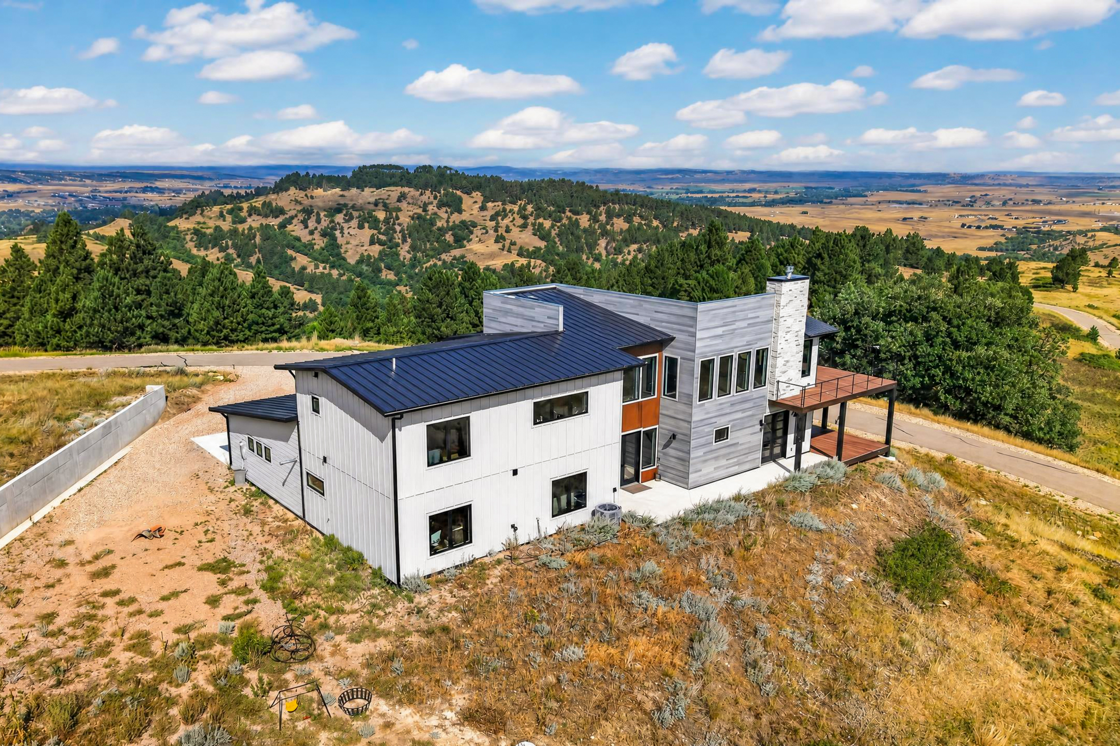 An aerial view shows the rear of the house perched above rolling