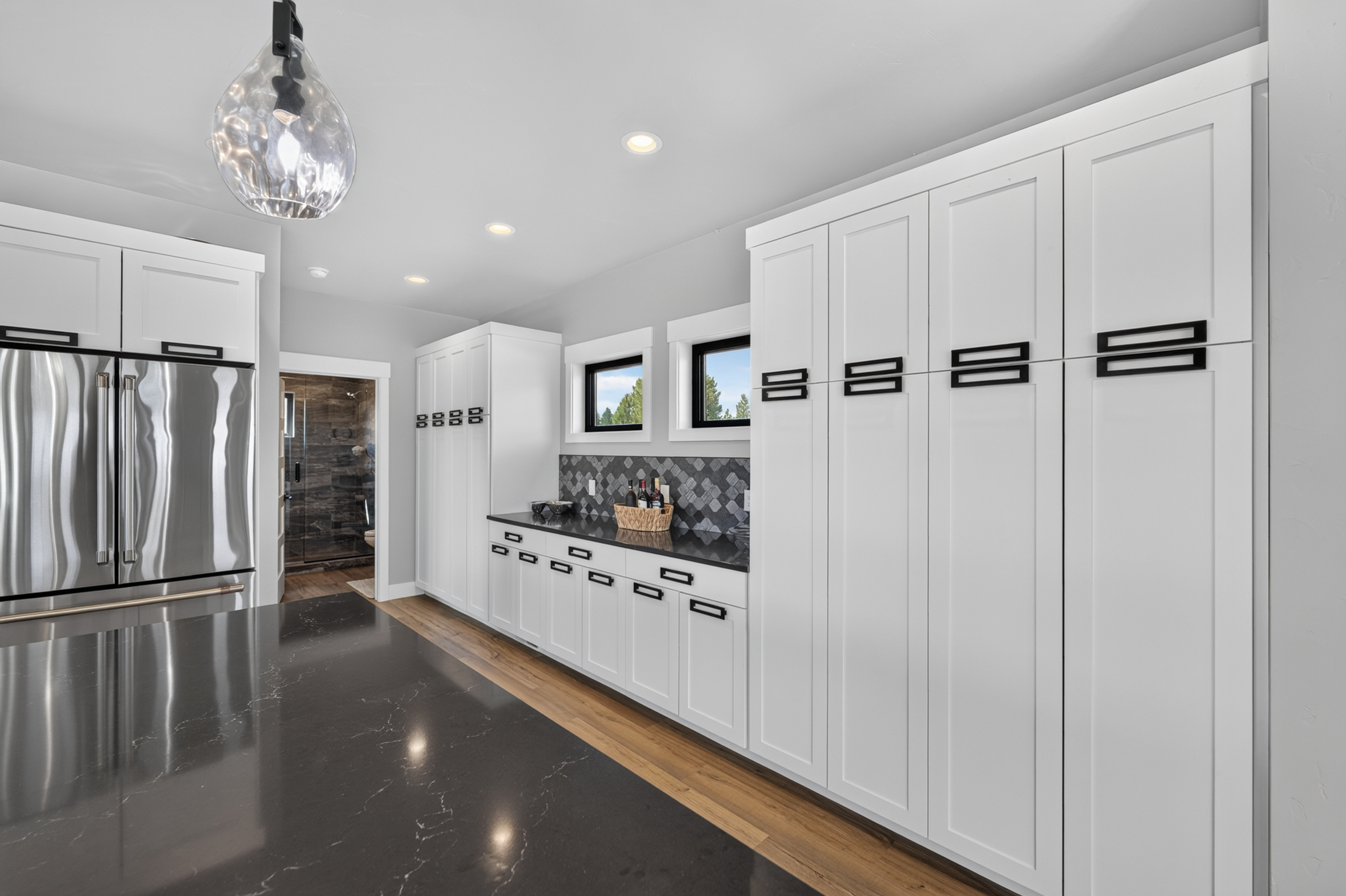 A butler's pantry area offers additional counter space and tall storage cabinets near the kitchen, with wine bottles set out on the counter.