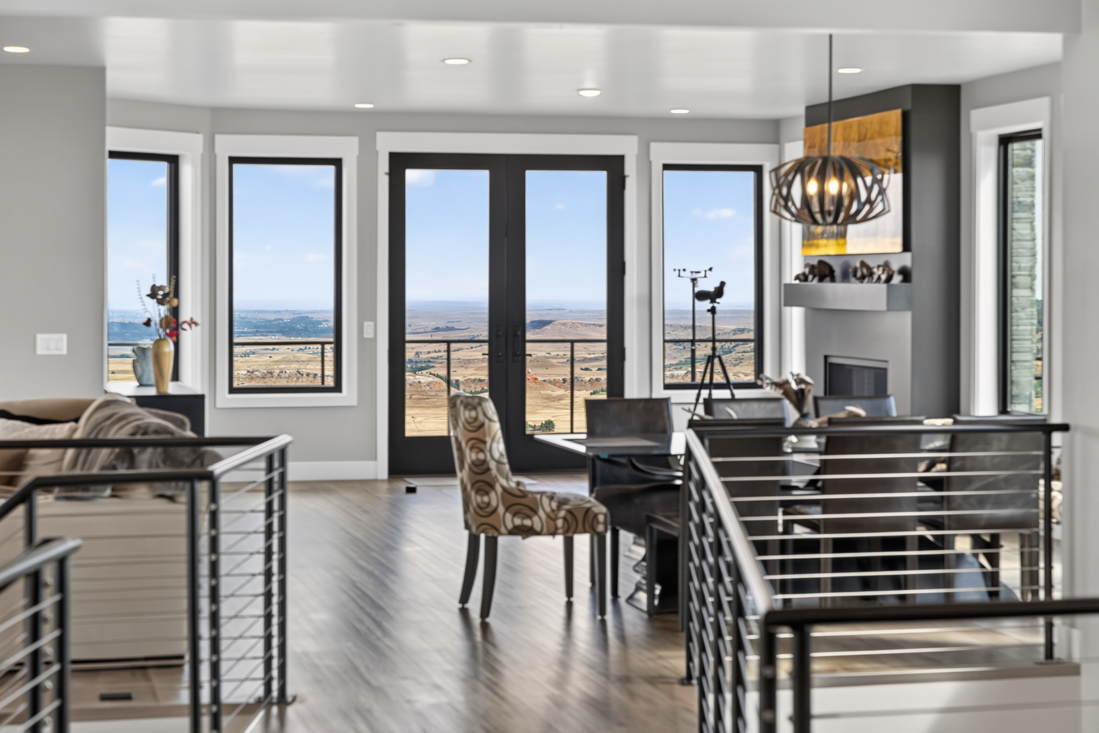 A small dining table sits before glass doors opening onto a deck
