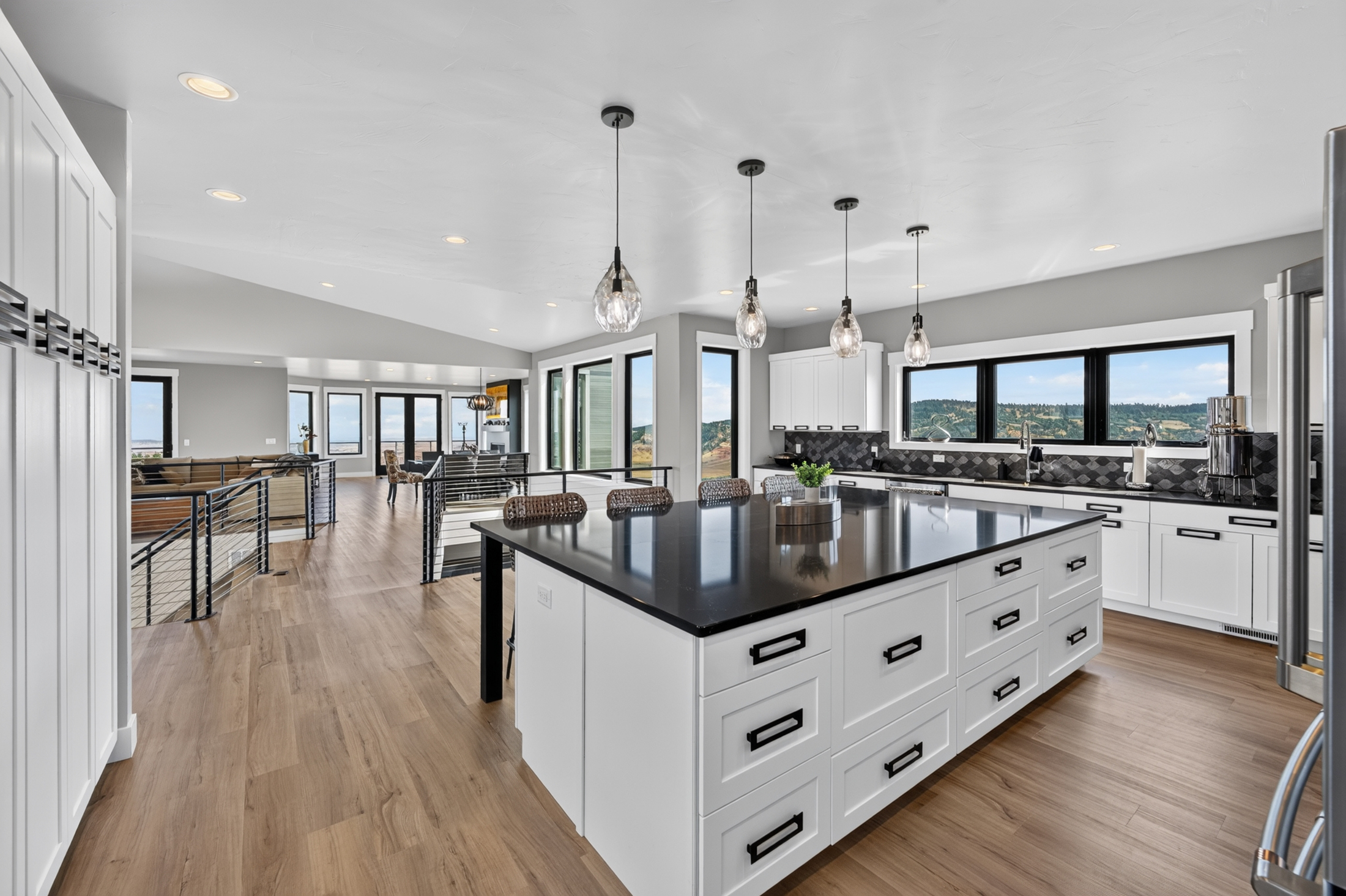 A run of white cabinetry and dark countertop leads from the kitchen toward the sunken living room at 2111 Vantage Circle.
