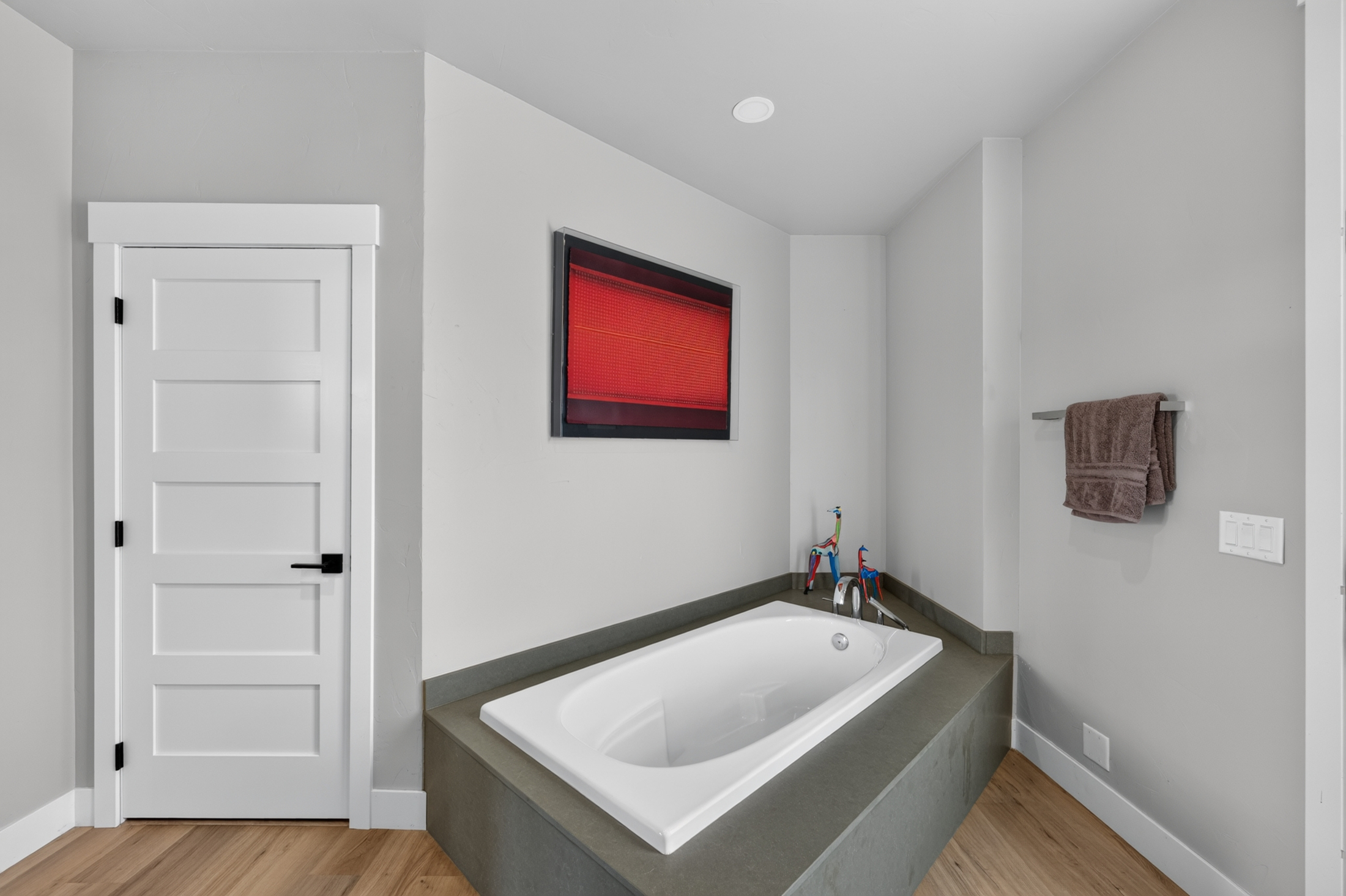 The bathroom's platform tub is framed by a vertical red abstract artwork and a nearby towel bar at 2111 Vantage Circle.