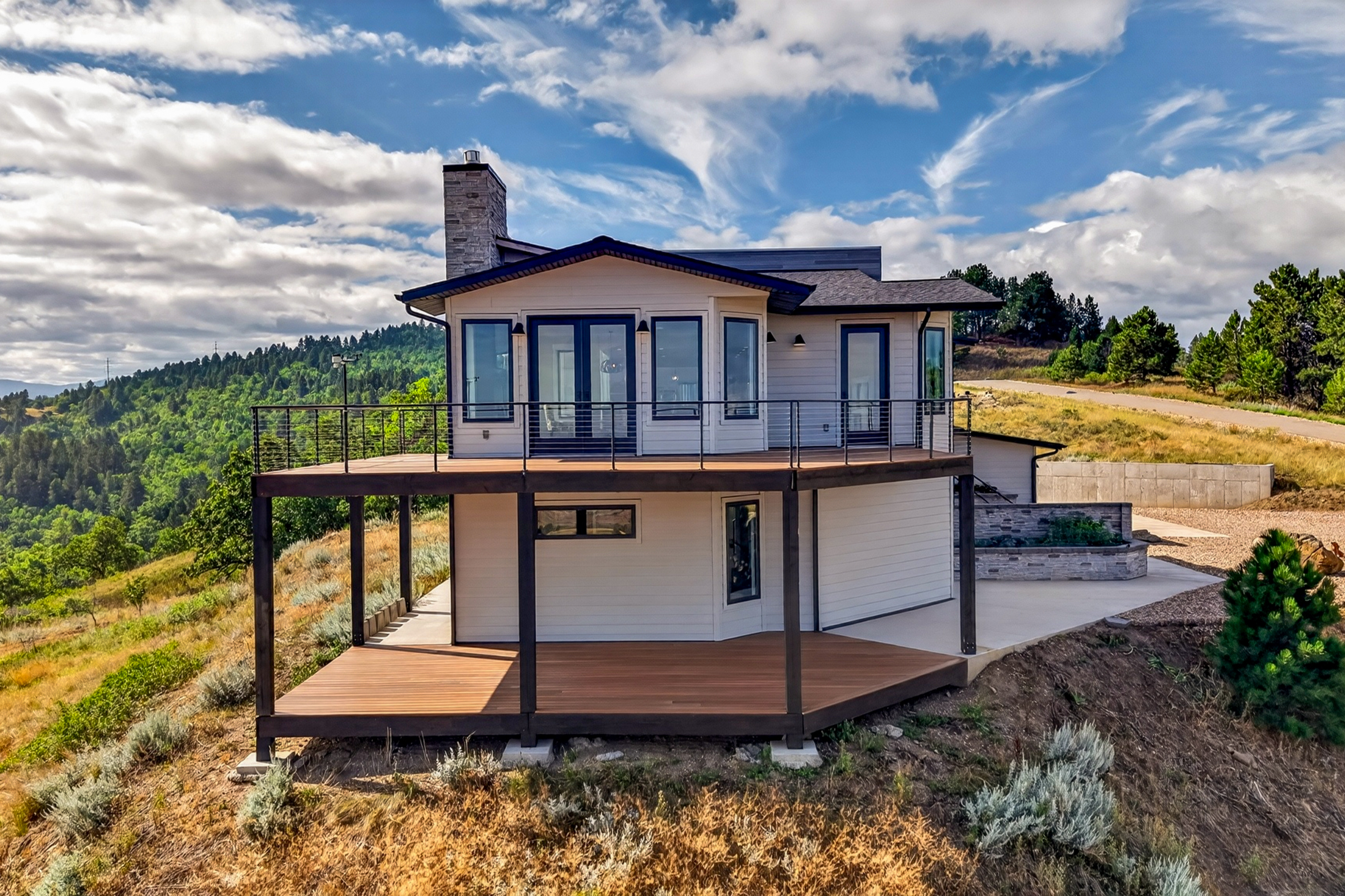 The rear of the house shows a cantilevered upper deck with glass and cable railing
